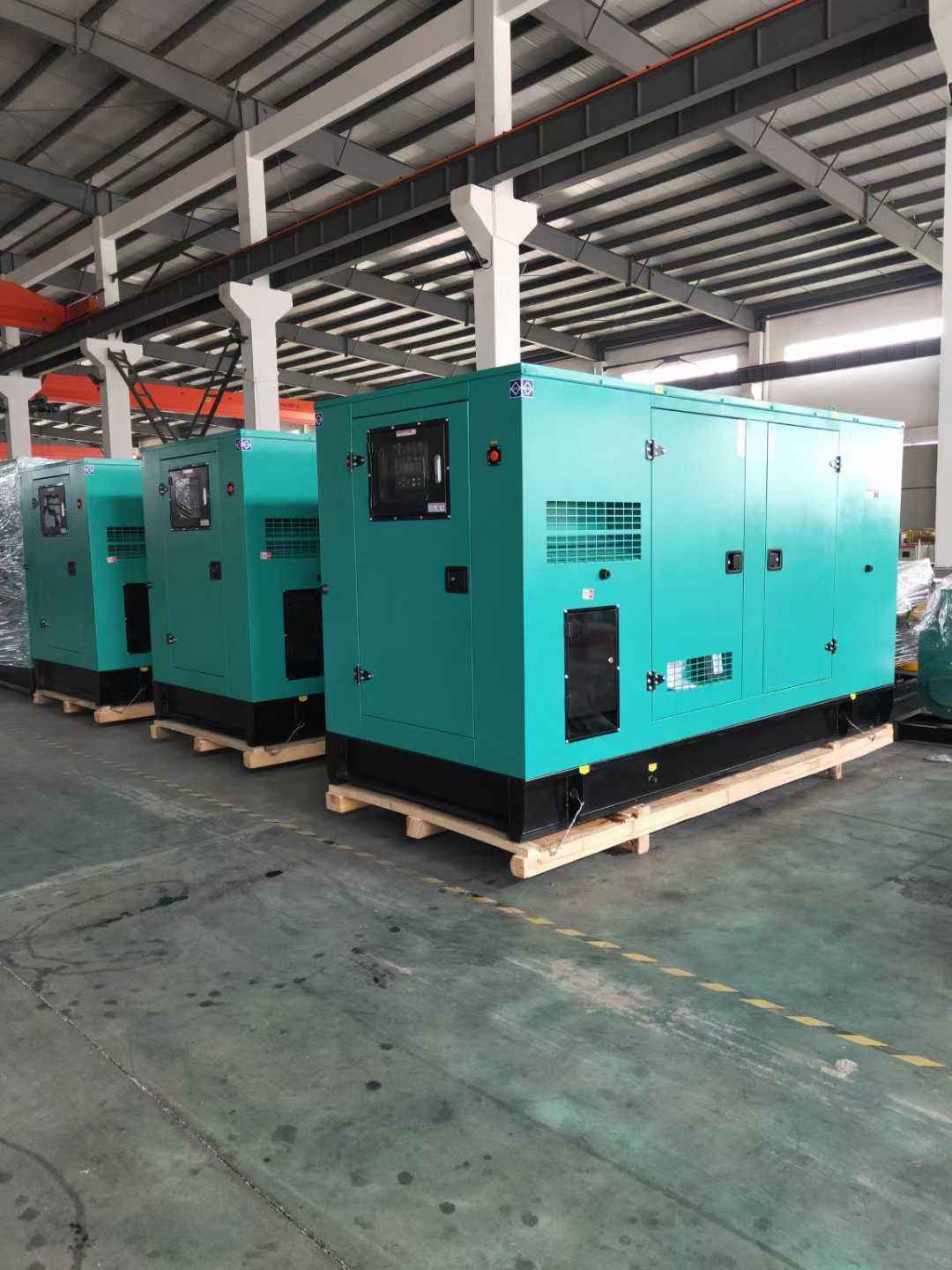 Three soundproof canopy hospital standby generator sets lined up in a workshop ready for deployment