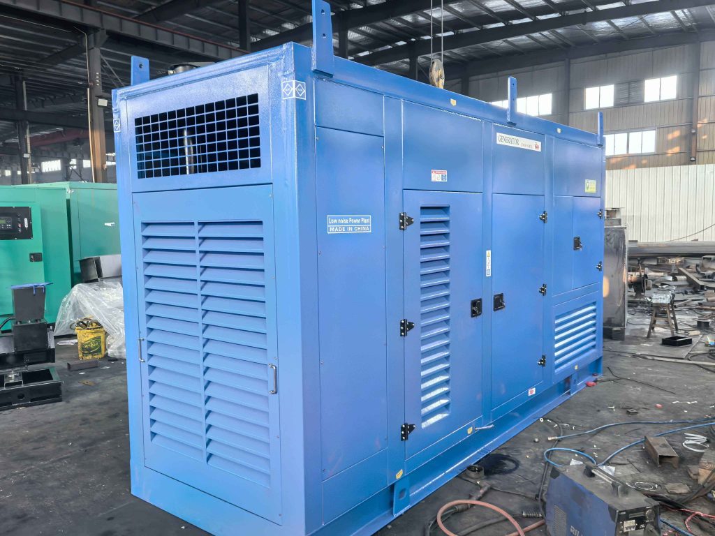 Blue soundproof canopy diesel generator set with louvred access doors standing inside a steel fabrication workshop